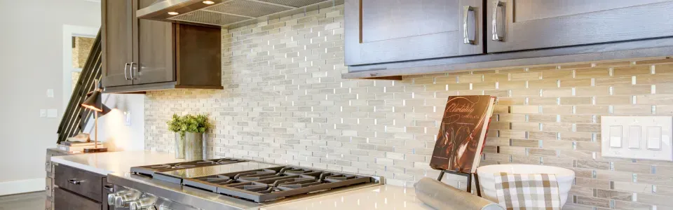 kitchen with full backsplash on the wall above a cream colored counter